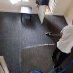 Person using a carpet cleaning tool on dark carpet