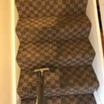 Close-up of a carpeted staircase being cleaned with a professional cleaning tool